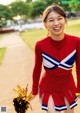 A woman in a cheerleading uniform holding a pom pom.