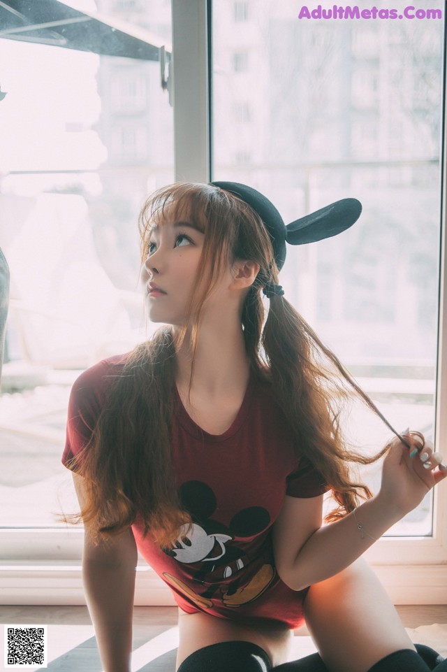 A woman sitting on the floor in front of a window.