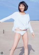 A woman in a white shirt and white panties on a beach.