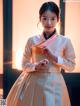 A woman in a white and pink hanbok poses for a picture.