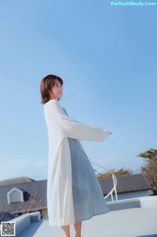 a woman standing on top of a roof with her arms outstretched