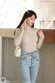 a woman in jeans and a turtle neck top talking on a cell phone