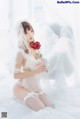 A woman in a white lingerie holding a red rose.