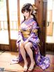 A woman in a kimono sitting on a wooden floor.