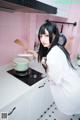 A woman standing in a kitchen holding a wooden spoon.