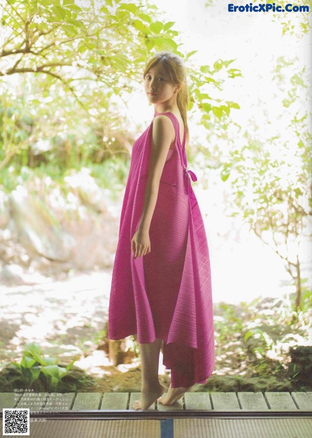 A woman in a pink dress standing on a wooden platform.
