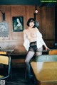 A woman in black stockings and a white shirt posing in a restaurant.